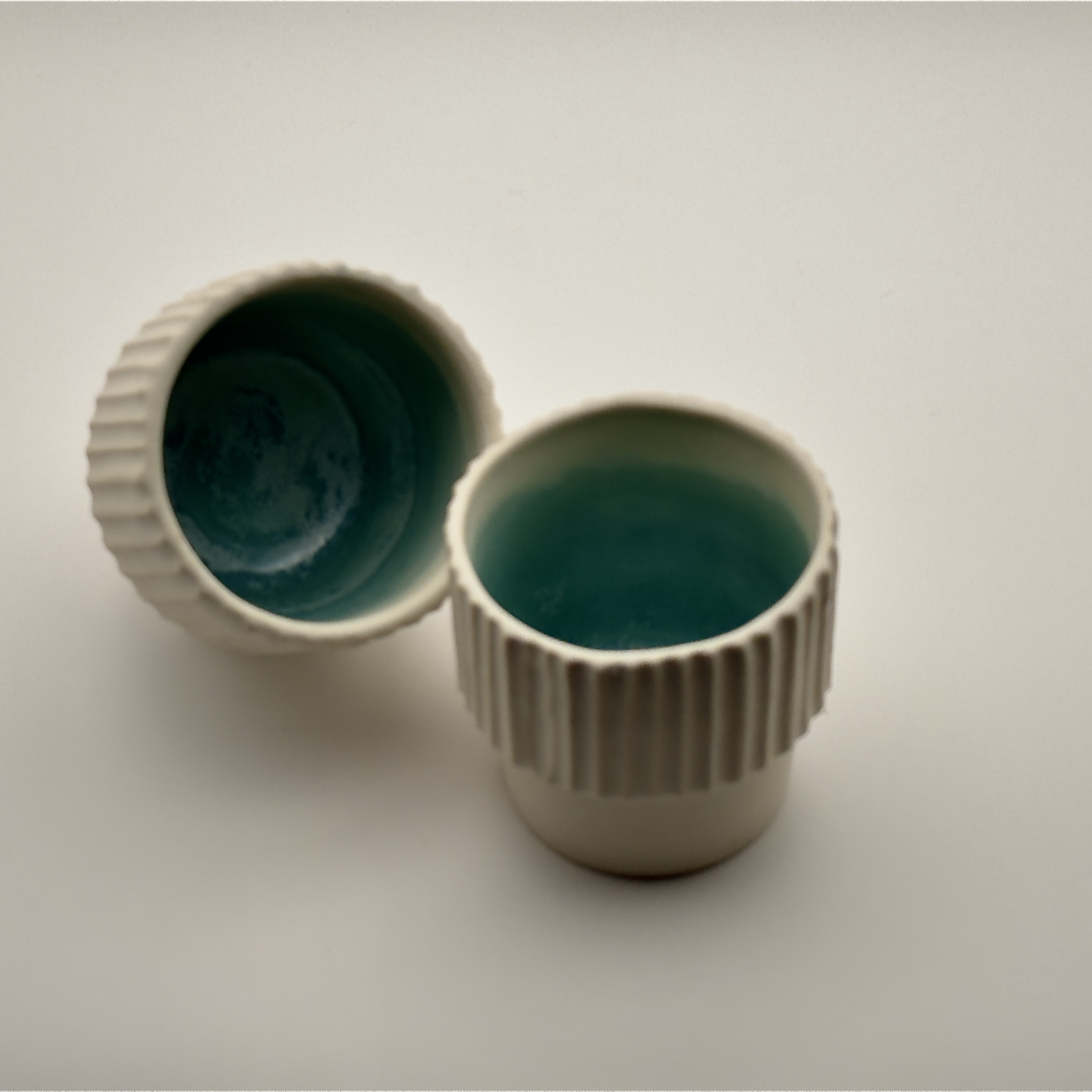 Fluted cream cup and teal-glazed bowl, close view