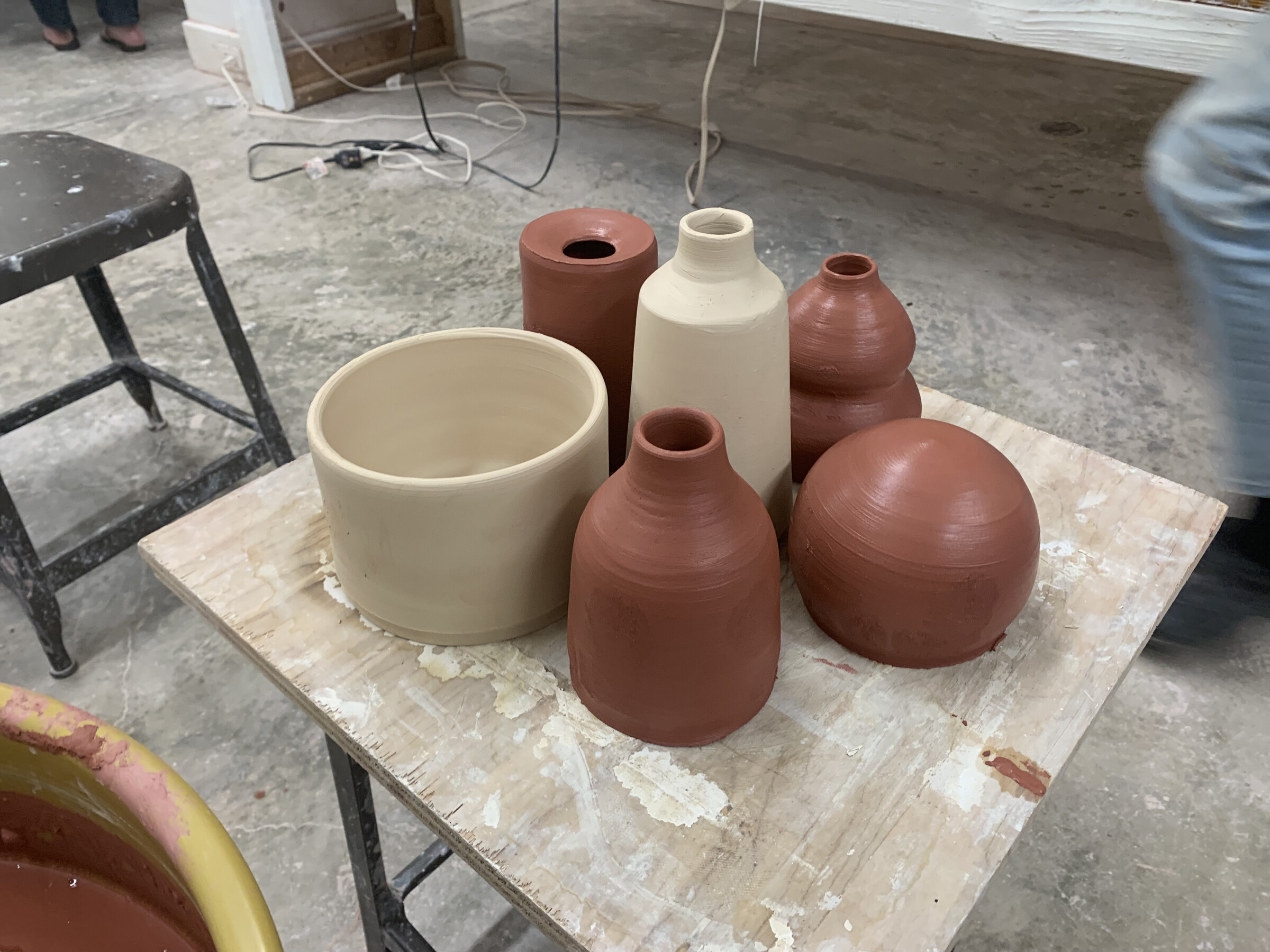 Greenware pots and vases arranged on a worktable in the studio