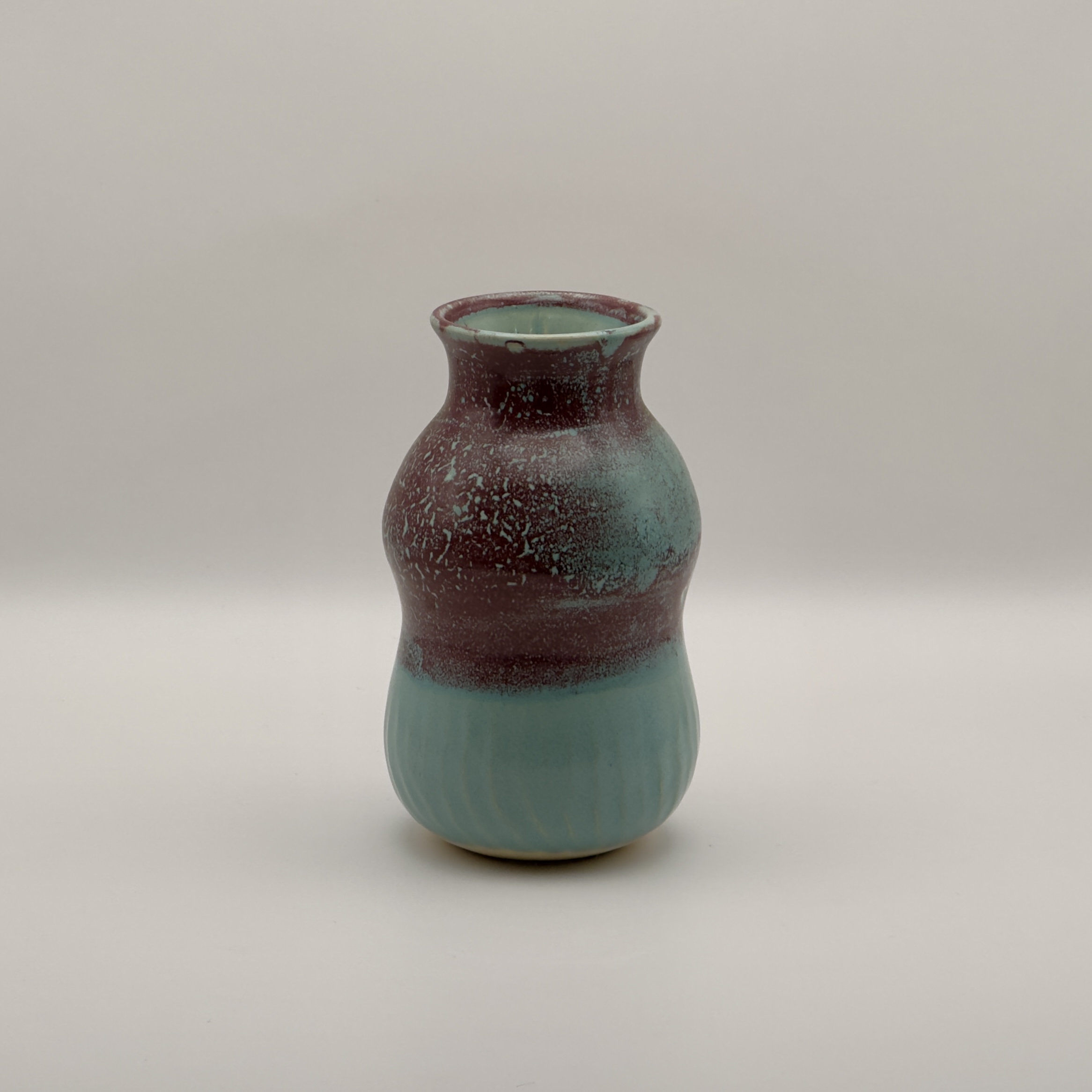 Small vase with a maroon top fading to teal, ringed neck
